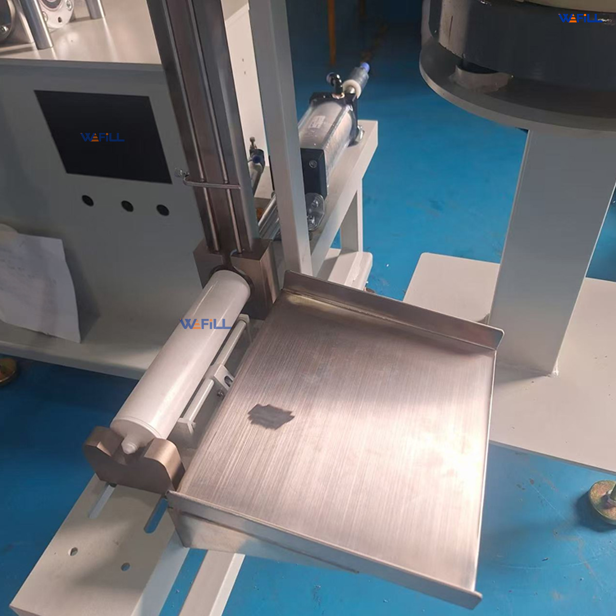 Photo of the vibratory cap feeder on a semi-automatic silicone sealant filling and capping machine, showing the sorting bowl and cap discharge track